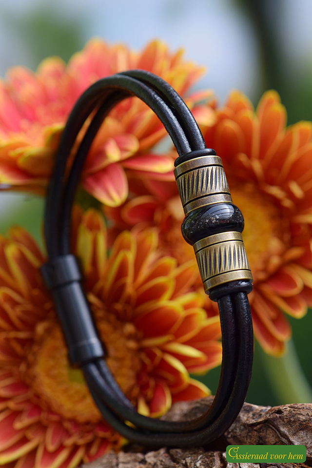 placed between vintage copper-tone beads on black leather strap.