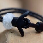 Double black leather bracelet with a transparent glass bead containing visible cremation ashes