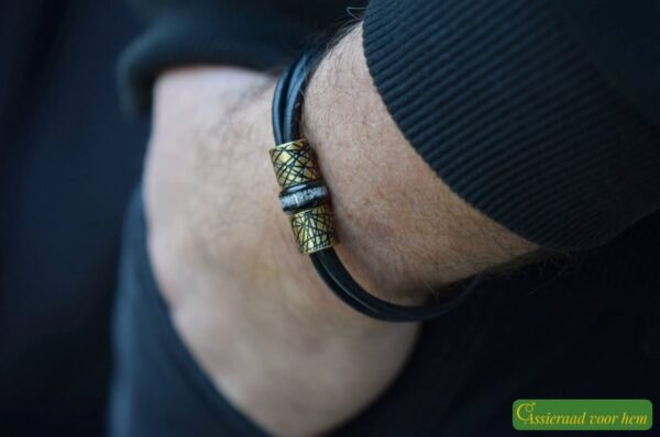 placed between black and gold stainless steel design beads on black leather strands.