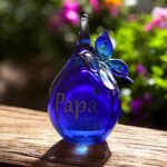 Urn and butterfly of dark blue transparent glass.