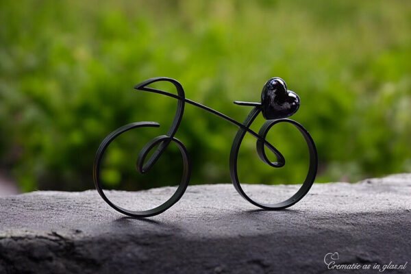 Elegant black metal racing bike with a black-transparent glass heart on the saddle