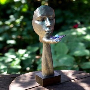 Silver-colored sculpture with face and hand