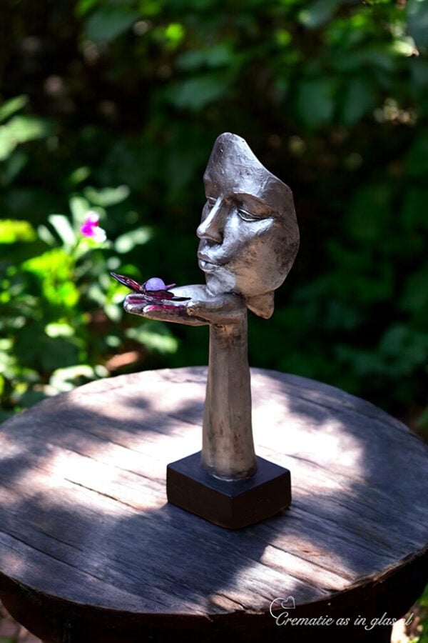 Silver-colored sculpture with face and hand