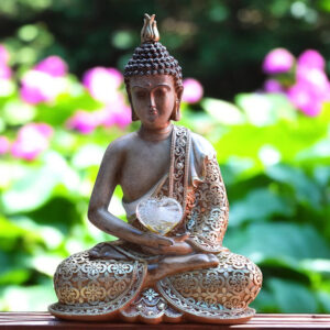 Buddha statue holding a gold-transparent glass heart with visible cremation ashes fused inside as a lasting tribute.