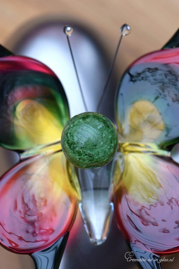 with transparent green mini urn containing visible cremation ashes.