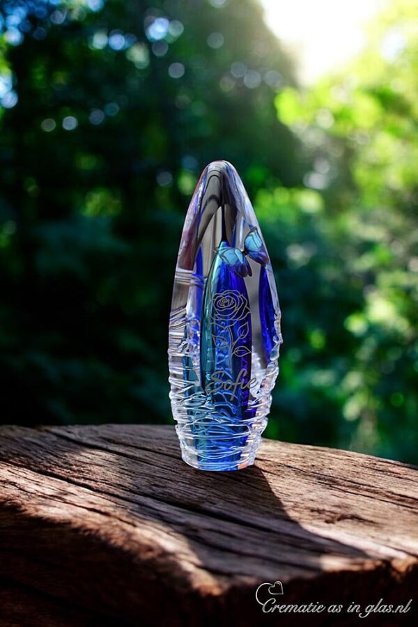 Design urn of glass Orion has a purple transparent ash chamber. A name is applied to the design urn of glass by means of silver sign foil. The cremation ash is placed in the bottom bell.