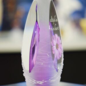Glass design urn with transparent purple and pink ash chamber and image of a purple flower with space for a short name – suitable for cremation ashes.