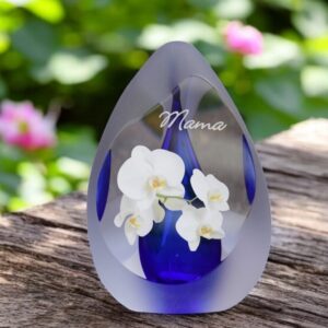 Design urn made of glass with transparent blue ash chamber and image of a white orchid – suitable for storing cremation ashes.