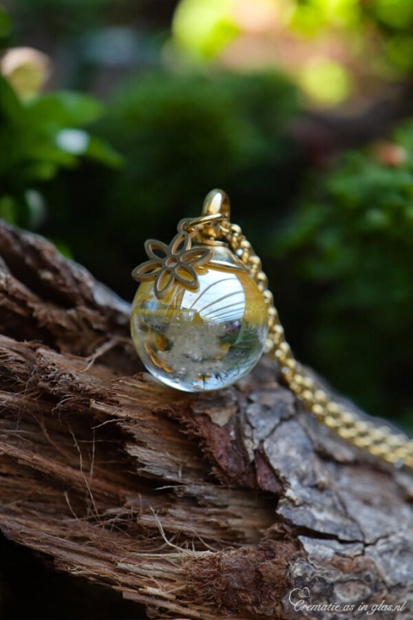 Memorial pendant with visible ashes in gold shimmering transparent glass and gold stainless steel bail.