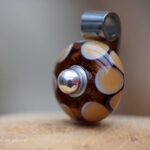 Memorial pendant with subtle ashes in dark brown dotted glass and 925 sterling silver bail