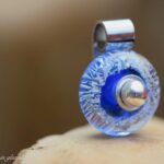 Memorial pendant with subtle ashes in blue and silver shimmering glass and 925 sterling silver bail