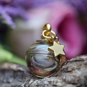 Memorial pendant with visible ashes or hair in brown