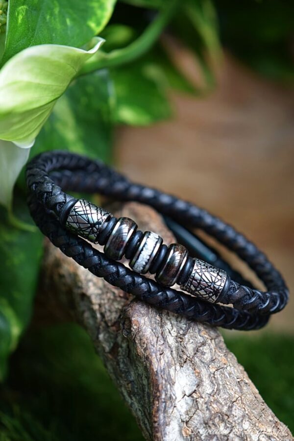 Men’s memorial bracelet with double black braided leather and three black beads containing visible hair and cremation ashes.