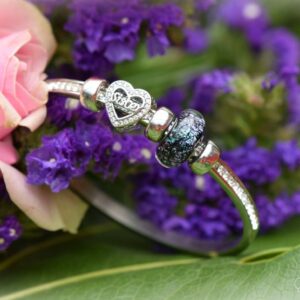 Memorial bangle with invisible ashes in black shimmer glass and sterling silver ‘Sister’ charm