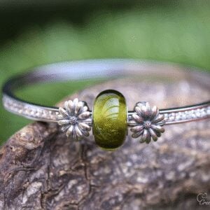 Memorial bangle with visible ashes in transparent olive green glass