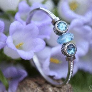 Memorial bangle with visible ashes in transparent blue glass and sterling silver beads with blue crystals