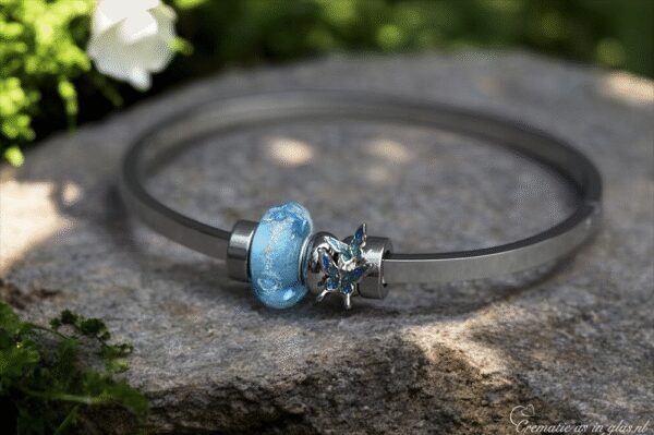 Memorial bangle with visible ashes in transparent blue glass
