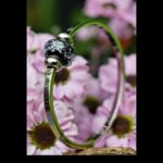 Memorial bangle with invisible ashes in black glass with colourful shimmer