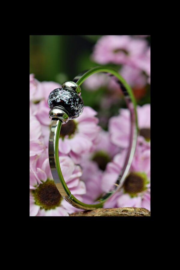 Memorial bangle with invisible ashes in black glass with colourful shimmer