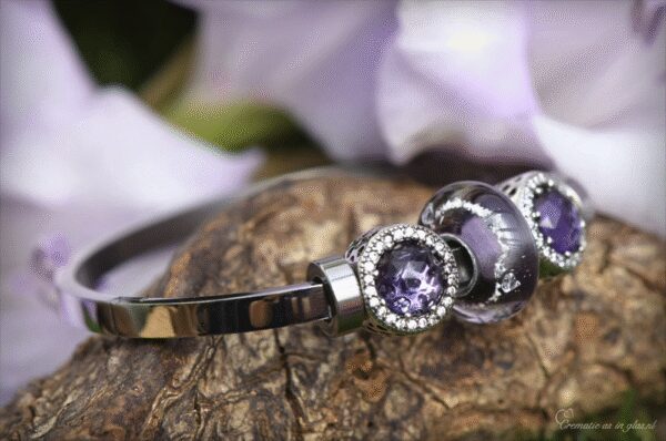 Memorial bangle with visible ashes in transparent purple glass and sterling silver bead charms with purple crystals and zirconia accents.