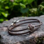 Memorial bracelet with cremation ashes fused in dark brown glass on custom brown leather with stainless steel clasp.