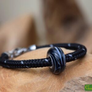 Men’s memorial bracelet with black sailrope band and black-and-white glass bead infused with cremation ashes.