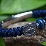 Men’s memorial bracelet in blue Sailrope with mottled blue cremation ashes glass bead beside a stainless steel anchor button bead.