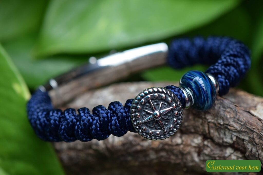 Men’s memorial bracelet in blue Sailrope with mottled blue cremation ashes glass bead beside a stainless steel anchor button bead.