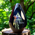 Glass design urn with green-yellow ash chamber and image of a robin on a tree trunk with space for a short name – suitable for cremation ashes.