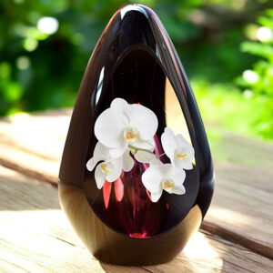 Design urn made of glass with transparent pink ash chamber and image of white orchids – suitable for cremation ashes.