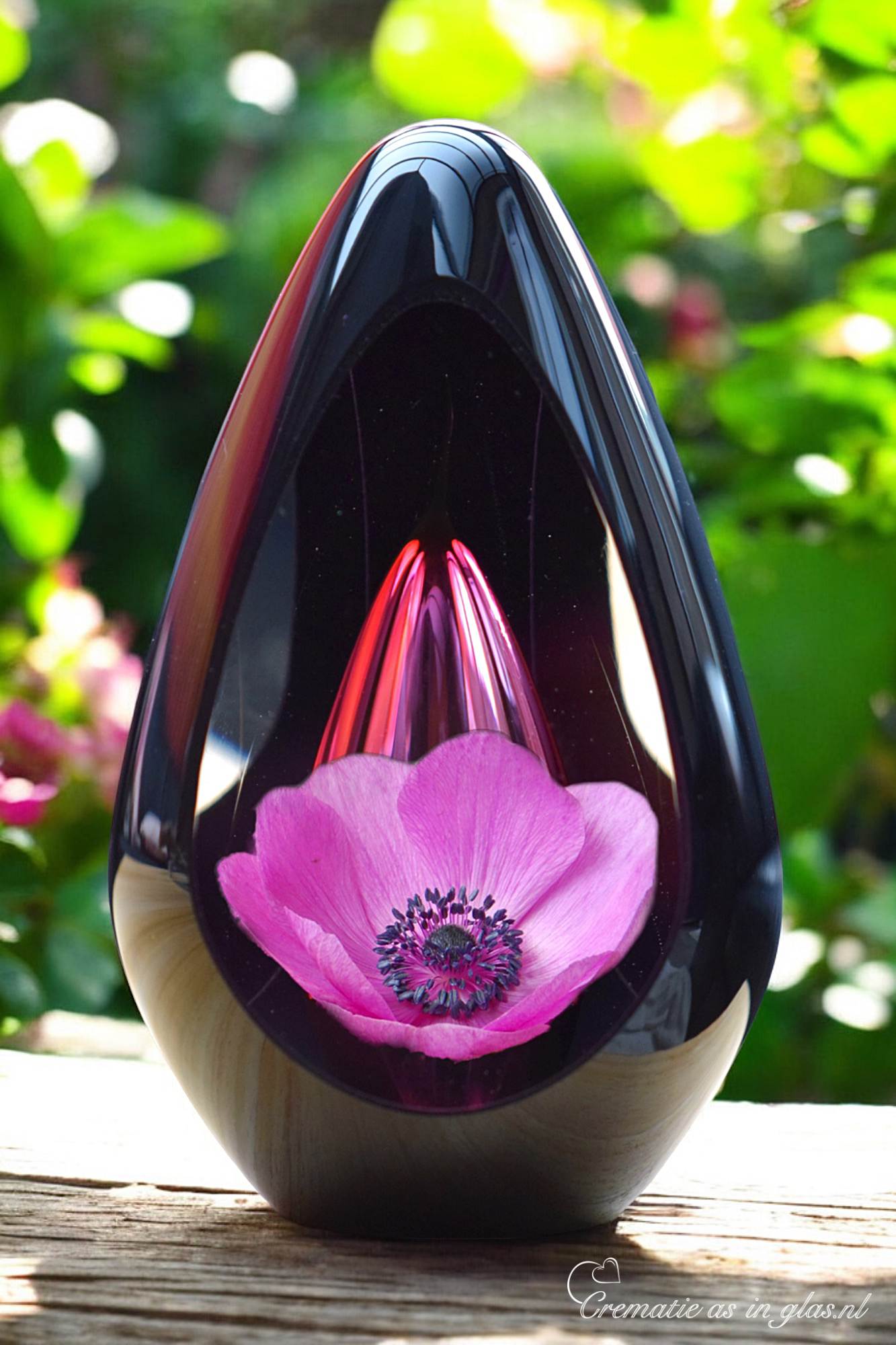 Design urn made of glass with transparent pink ash chamber and image of a pink poppy – suitable for cremation ashes.