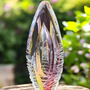Design urn made of glass with transparent pink-yellow ash chamber and 3D lines of molten glass – suitable for cremation ashes.