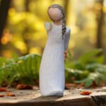 Willow Tree figurine For You with girl holding yellow flowers behind her back and a glass mini urn on her shoulder.