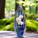 Design urn made of glass with transparent blue ash chamber and image of a white orchid – suitable for storing cremation ashes.
