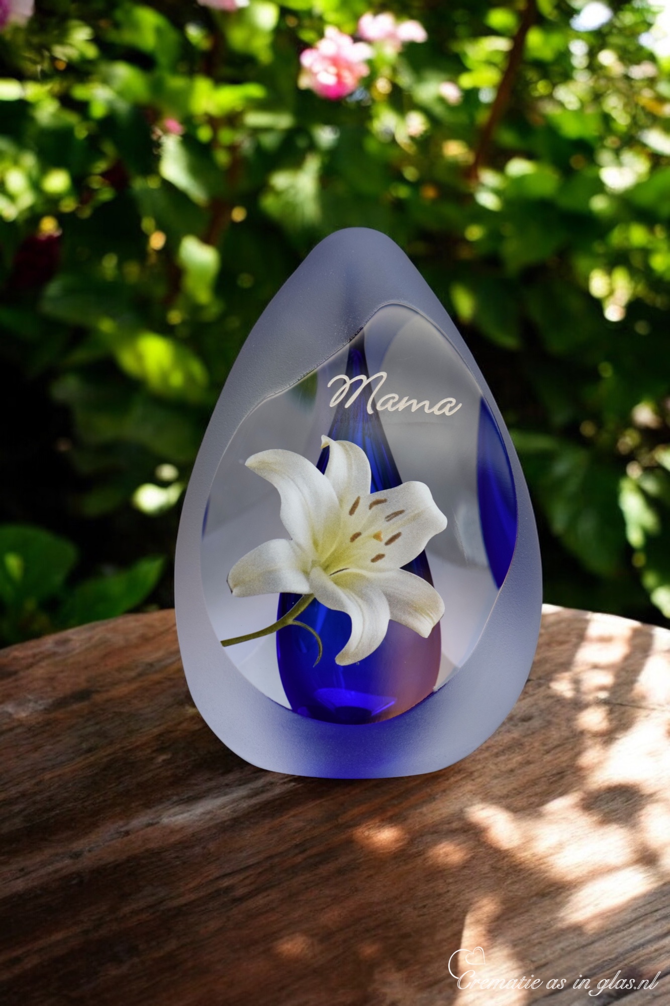 Design urn made of glass with transparent blue ash chamber and image of a white lily – suitable for storing cremation ashes.