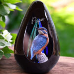 Design urn made of glass with purple-pink ash chamber and subtle pattern of air bubbles above the ash chamber – for cremation ashes.