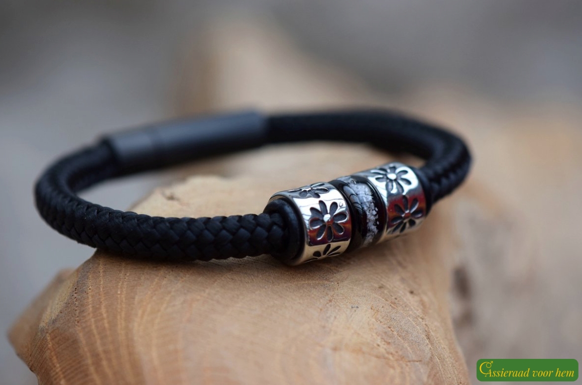 Black sailrope bracelet with ashes bead between stainless-steel design beads with floral pattern.