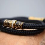 Men’s memorial bracelet in black sailrope with cremation ashes in gold stainless-steel bead and gold clasp.