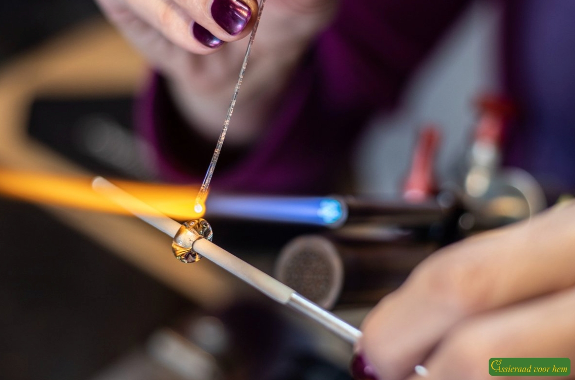 Detail of transparent green cremation ashes glass bead between silver stainless-steel stoppers.