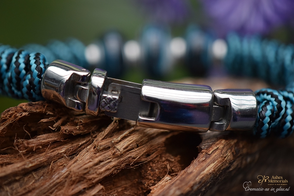 Men’s memorial bracelet with turquoise-black knotted band and petrol cremation ashes glass bead worn on the wrist.