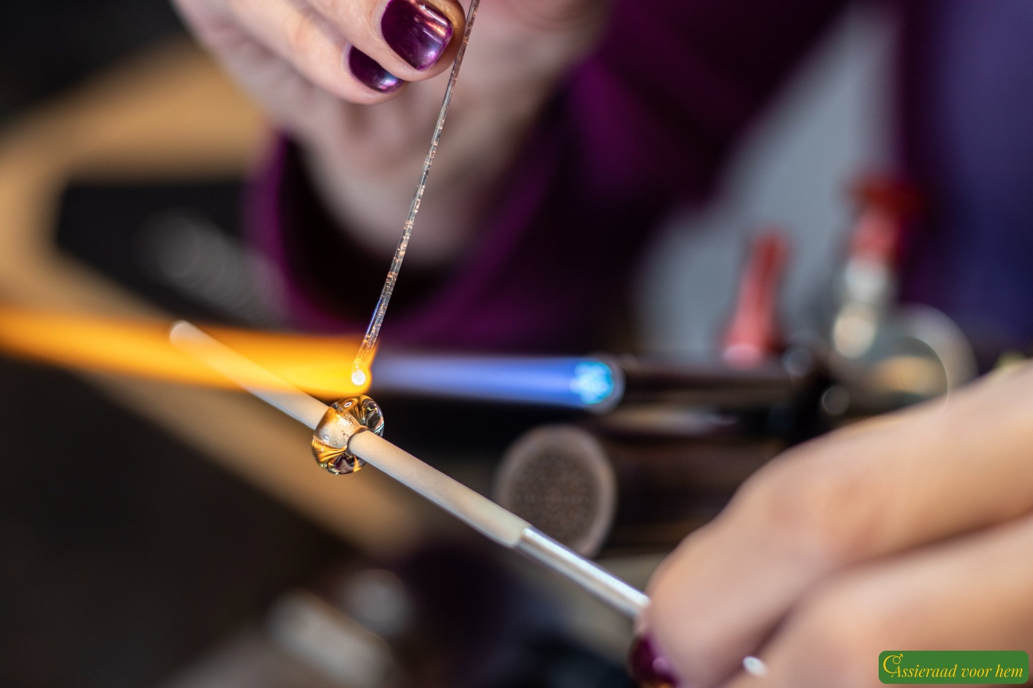 Close-up of lilac cremation ashes glass bead between two purple beads on a purple Sailrope bracelet.
